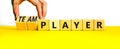 Player or teamplayer symbol. Businessman turns wooden cubes and changes concept words Player to Teamplayer. Beautiful yellow table Royalty Free Stock Photo