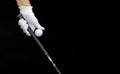 Close-up of a hand wearing a golf glove holding a golf ball and a golf club between the fingers Royalty Free Stock Photo