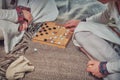 Players at the Board game in vintage style - tafl, hnefatafl. Two people play tavlei, closeup Royalty Free Stock Photo