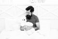 Playful adult. Cute and romantic. Bearded hipster play toy. Valentines day gift. Man hug soft toy relaxing in bed. Make