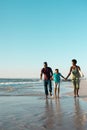 Playful african american boy holding father and mother's hands and running in sea against sky Royalty Free Stock Photo