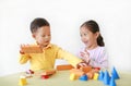 Playful asian little girl and baby boy playing a colorful wood block toy on table over white background. Sister and her brother Royalty Free Stock Photo