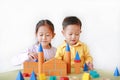 Playful asian little girl and baby boy playing a colorful wood block toy on table over white background. Sister and her brother Royalty Free Stock Photo