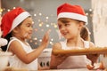 Playful bakers. Two little girls wearing santa hats baking in the kitchen. Royalty Free Stock Photo