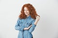 Playful beautiful redhead girl smiling touching hair looking at camera over white background. Royalty Free Stock Photo