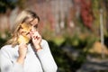 Playful blond woman white sweater, holding golden foliage yellow leaves maples two hands,hiding face, blurred. Close up Royalty Free Stock Photo