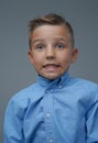 Playful boy making face and posing against grey background Royalty Free Stock Photo