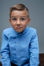 Playful boy making face and posing against grey background Royalty Free Stock Photo