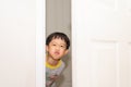 A playful boy peeking from behind the door