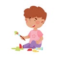 Playful Boy in Stained Clothes Sitting and Holding Paintbrushes and Paints Vector Illustration