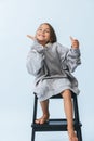 Playful cheerful little girl in oversize hoodie sitting on a stepping stool