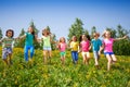 Playful children run, hold hands in green field
