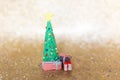 Playful clay christmas concept. Colorful handmade miniature Christmas tree and presents in gold background