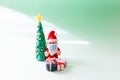 Playful clay christmas concept. Colorful handmade miniature Christmas tree, presents and Santa Claus with mask on green background