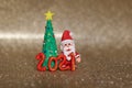 Playful clay christmas concept. Colorful handmade miniature Christmas tree and Santa Claus in gold background. 2021 new year