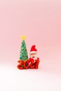 Playful clay christmas concept. Colorful handmade miniature Christmas tree and Santa Claus on pink background. 2021 new year