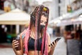 Playful cool rebel funky hipster young girl with face mask searching for playlist music on mobile phone while walking on city Royalty Free Stock Photo