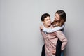 Playful couple riding piggy back together laughing as they young woman rides on her husbands piggy back, on grey background Royalty Free Stock Photo
