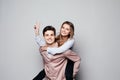 Playful couple riding piggy back together laughing as they young woman rides on her husbands piggy back, on grey background Royalty Free Stock Photo