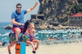 Playful crazy man dad riding wooden rocking horse at beach, Happy adult guy having fun on playground in summer vacation Royalty Free Stock Photo
