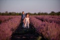 Playful cute boy girl are playing in rows of lavender purple field at sunset. Small couple. Allergy