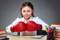 Playful cute little girl having fun in boxing gloves while leaning on grey background, selective focus Royalty Free Stock Photo