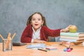 A playful cute little girl is having fun while relying on thick books on a gray background. Her hair is made in Royalty Free Stock Photo