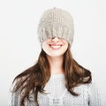 Playful cute winter girl covers eyes with hat