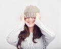 Playful cute winter girl covers eyes with hat