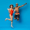 Playful energetic african american couple jumping on blue