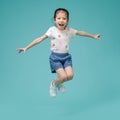 Playful energetic Asian little girl jumping in mid-air