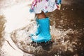 Cheerful small girl having fun in puddle on street