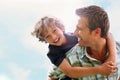 Playful father giving his son piggy back ride against sky. Portrait of a playful father giving his son piggy back ride Royalty Free Stock Photo