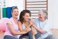 Playful female friends sitting in gym