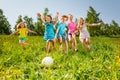 Playful friends running to the ball in field Royalty Free Stock Photo