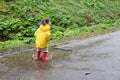 Playful girl wearing yellow raincoat while jumping in puddle during rainfall Royalty Free Stock Photo