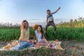 Playful happy family enjoying picnic together , beautiful young mom in yellow shirt sitting on the plaid with her Royalty Free Stock Photo