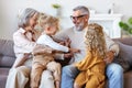 Kids and grandmother tickling grandpa while having fun at home, happy family senior grandparents and children having fun together Royalty Free Stock Photo