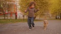 Playful kids running with dog on autumn street. Happy boy and girl running with cute cocker spaniel on pathway in autumn