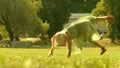 Playful little blonde girl performs handspring on a green park lawn on a sunny summer day