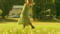 Playful little blonde girl performs handspring on a green park lawn on a sunny summer day