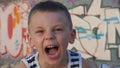 Playful little boy in a striped shirt who yells, grimaces and smiling