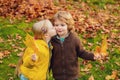 Playful little cute couple boy and girl walk on autumn park, have fun, kiss, enjoy good sunny day. Royalty Free Stock Photo