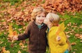 Playful little cute couple boy and girl walk on autumn park, have fun, kiss, enjoy good sunny day. Royalty Free Stock Photo