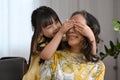 Playful little girl closing eyes her grandmother and having fun spending weekend time together. Multi generational Royalty Free Stock Photo