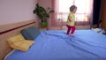 Playful little girl kid jump and run on bedroom bed