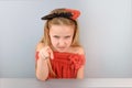 Playful little girl in red demon costume portrays an evil face and pointing finger at you