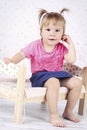 Playful little girl sitting on the small wooden bed