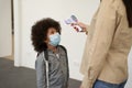 Playful little school boy wearing face mask waiting while his teacher measuring temperature, screening kid with digital Royalty Free Stock Photo