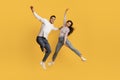 Playful Mood. Happy Middle Eastern Couple Jumping In Air Over Yellow Background Royalty Free Stock Photo